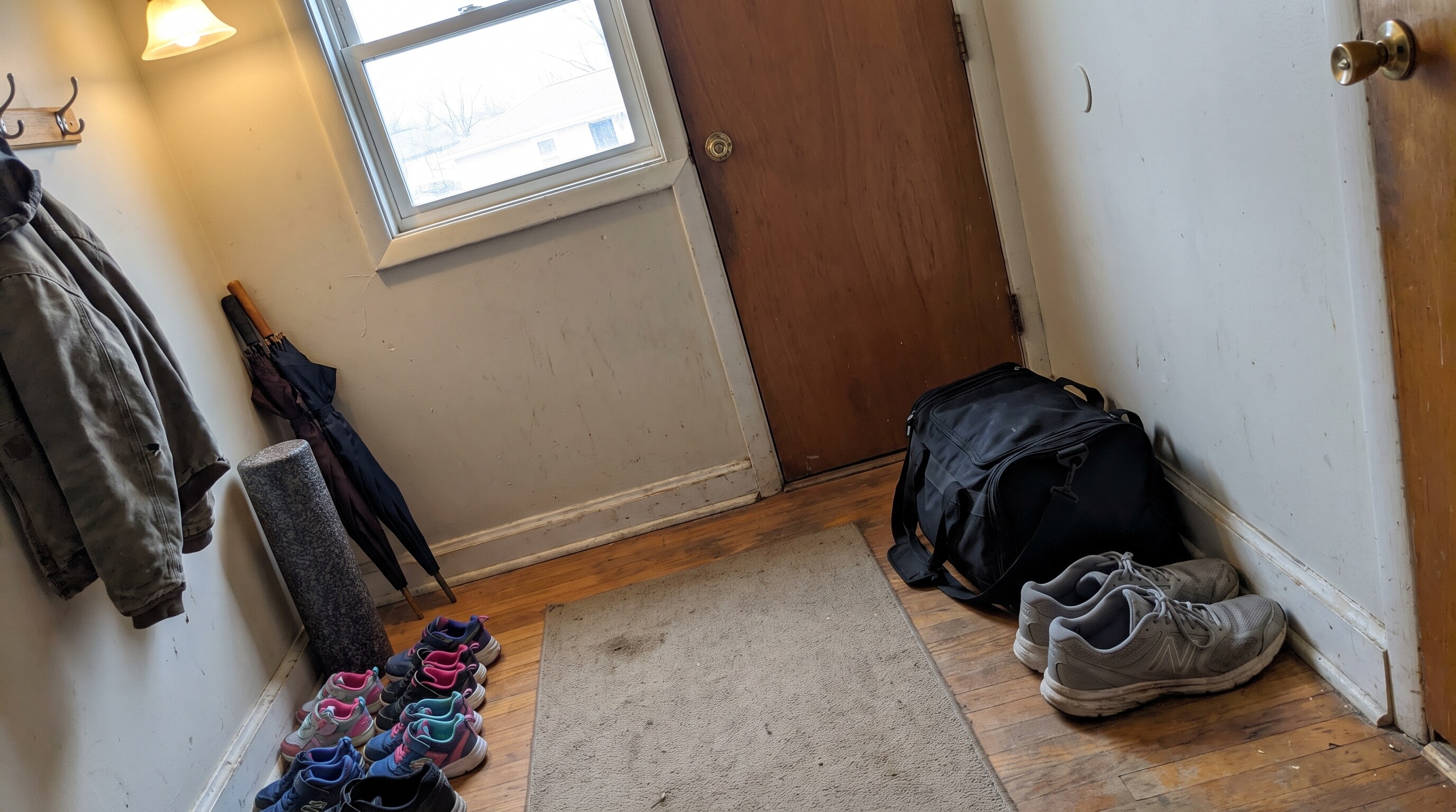 A zipped gym bag and running shoes left by the front door during the lazy week before a marathon
